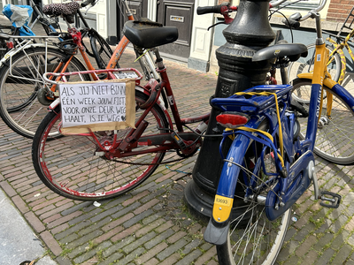 913001 Afbeelding van een fiets tegen een lantaarnpaal in de Lange Nieuwstraat te Utrecht, waarop buurtbewoners een ...